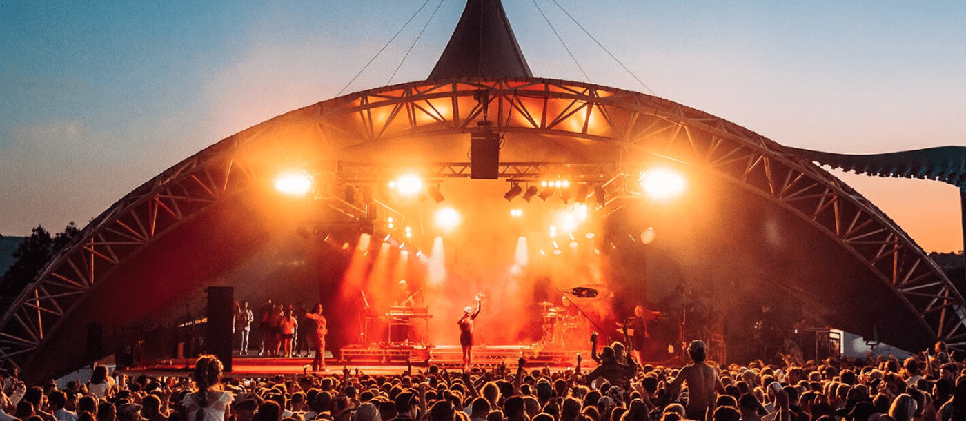 Outside stage with orange lighting showing performer and the crowd